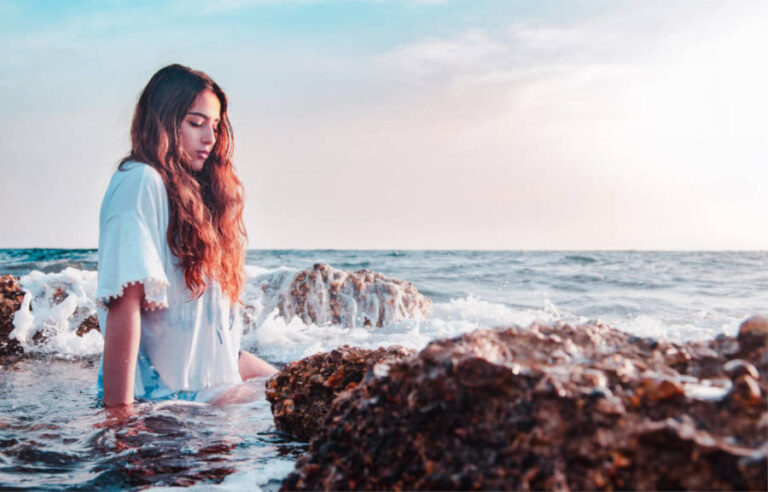 eine Frau sitzt im Meer und fragt sich wie wird man eine Meerjungfrau